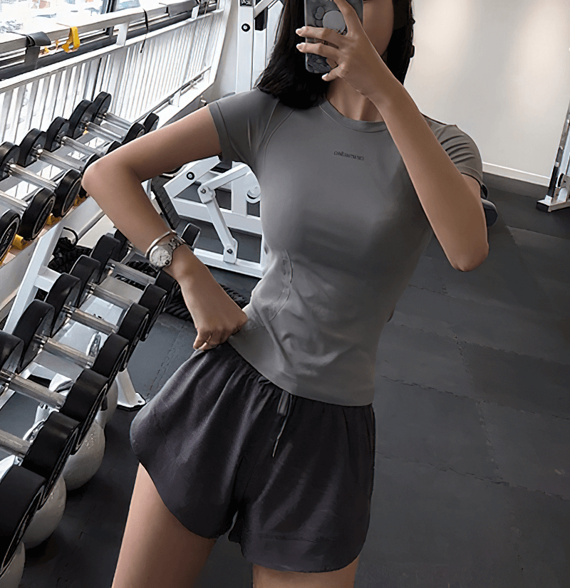 Woman in gym wearing breathable short-sleeve running t-shirt, showcasing sleek reflective design, perfect for fitness workouts and running.